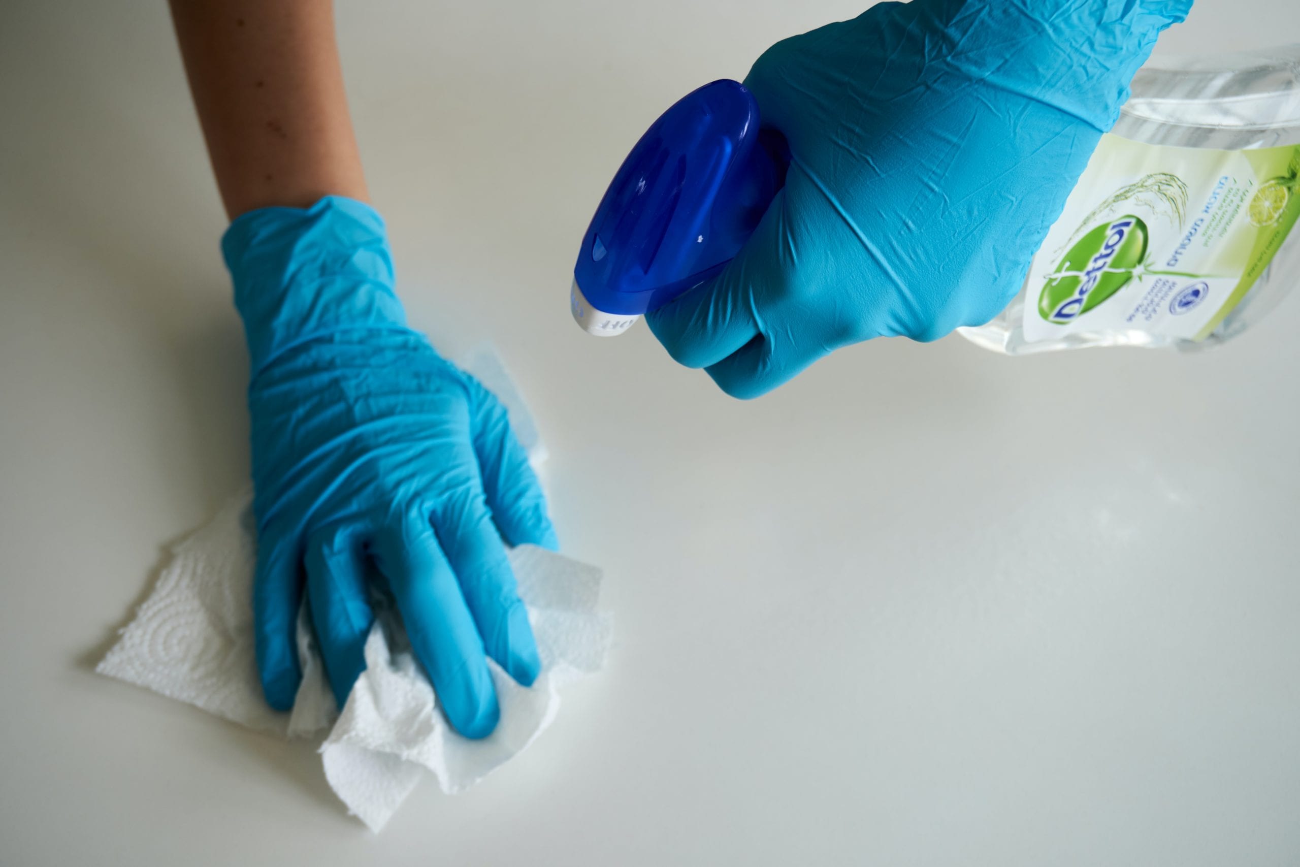 person spraying disinfectant on paper towel